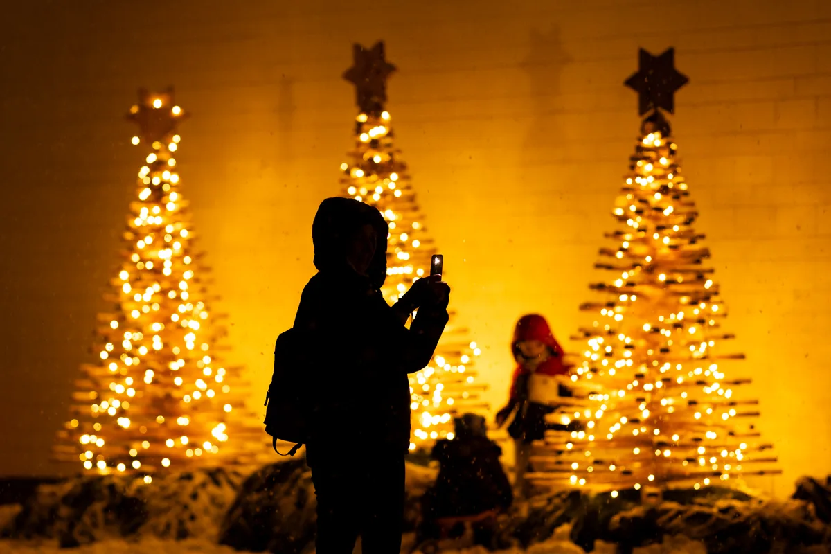 Im «Gwunderland» hat es an jeder Ecke ein Fotomotiv. Silhouette einer Person, die beleuchtete Weihnachtsbäume fotografiert.